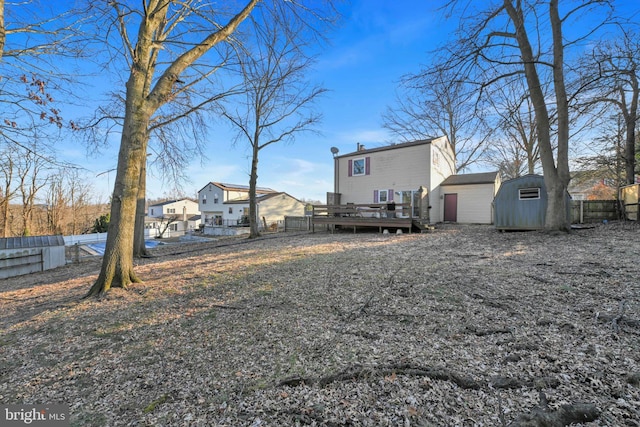 view of yard featuring a storage unit, fence, a deck, and an outdoor structure