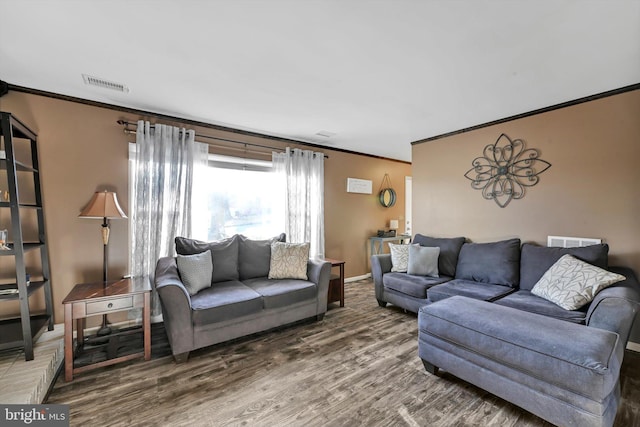 living area with ornamental molding, wood finished floors, visible vents, and baseboards