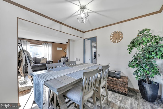 dining space featuring a chandelier, wood finished floors, visible vents, baseboards, and ornamental molding