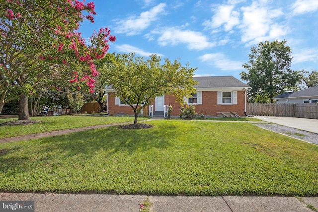 view of front of house featuring brick siding, fence, and a front lawn