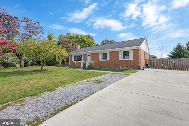 ranch-style home featuring brick siding, fence, a chimney, and a front lawn