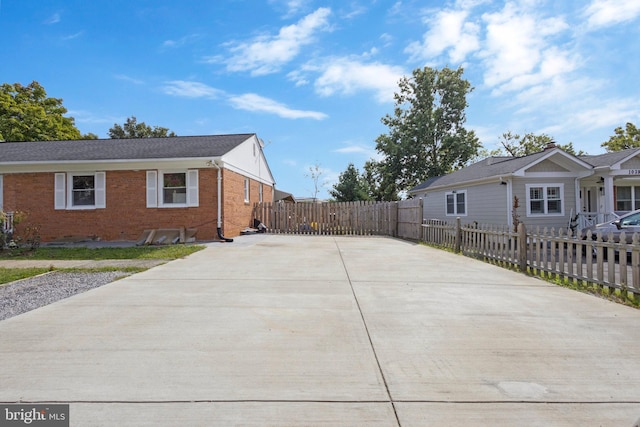 view of side of property with concrete driveway, brick siding, and a fenced front yard