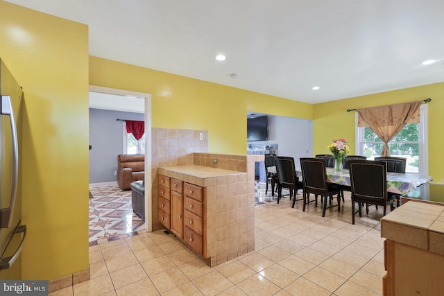 kitchen with recessed lighting, freestanding refrigerator, tile countertops, and light tile patterned floors