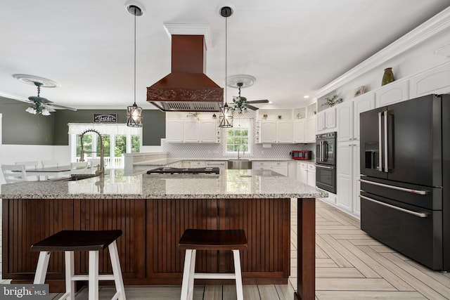 kitchen featuring ceiling fan, white cabinets, a wealth of natural light, black appliances, and island exhaust hood