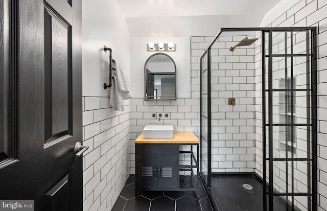 bathroom with a stall shower, tile walls, vanity, and tile patterned floors