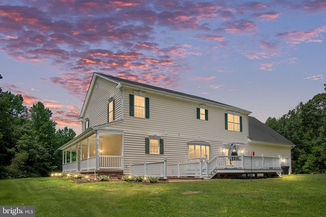 back of house at dusk with a lawn and a wooden deck