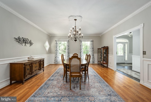 dining space featuring a chandelier, wainscoting, wood finished floors, and crown molding