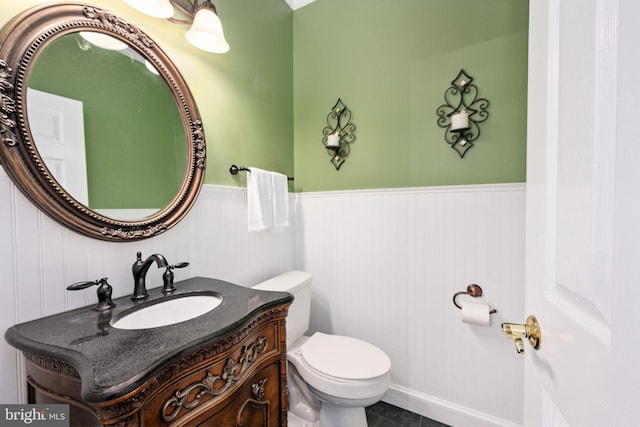 bathroom with toilet, vanity, and wainscoting