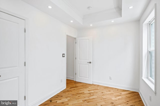 spare room with ornamental molding, a tray ceiling, light wood-style floors, and recessed lighting