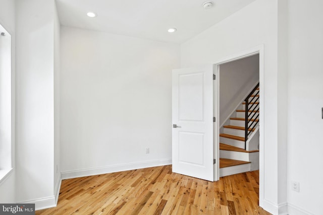 empty room with stairs, recessed lighting, light wood-type flooring, and baseboards