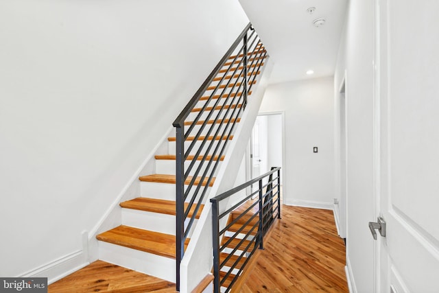 staircase featuring baseboards, wood finished floors, and recessed lighting