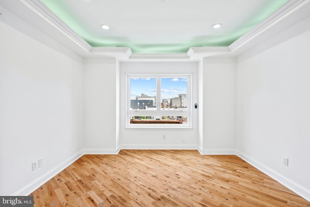 spare room featuring baseboards, wood finished floors, and crown molding