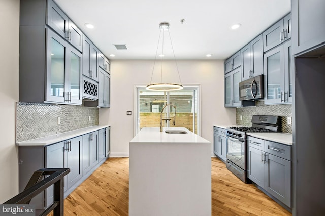 kitchen with light wood finished floors, light countertops, appliances with stainless steel finishes, and a sink