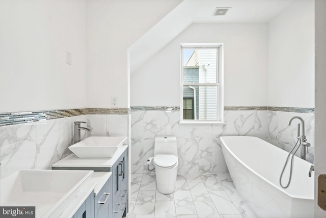 full bathroom featuring visible vents, toilet, marble finish floor, a freestanding bath, and vanity