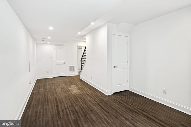 below grade area with stairway, baseboards, dark wood-style floors, and visible vents