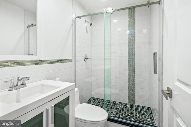 bathroom with toilet, vanity, tile walls, tasteful backsplash, and a stall shower