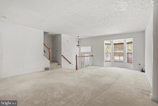 unfurnished living room featuring carpet, stairway, and a textured ceiling