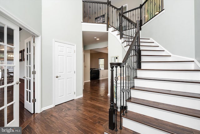 foyer with wood finished floors, a towering ceiling, baseboards, french doors, and stairway