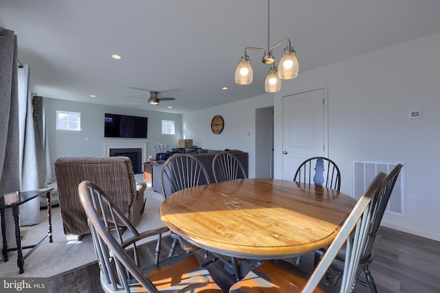 dining space with dark wood-style floors, a fireplace, visible vents, and recessed lighting