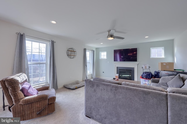 living room with a glass covered fireplace, light carpet, plenty of natural light, and recessed lighting