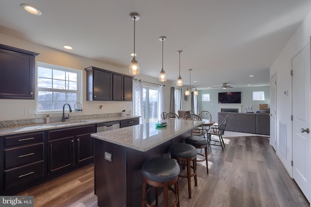 kitchen featuring light stone counters, a breakfast bar area, dark wood-type flooring, a fireplace, and open floor plan