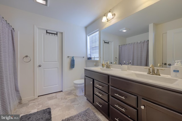 bathroom featuring double vanity, baseboards, toilet, and a sink