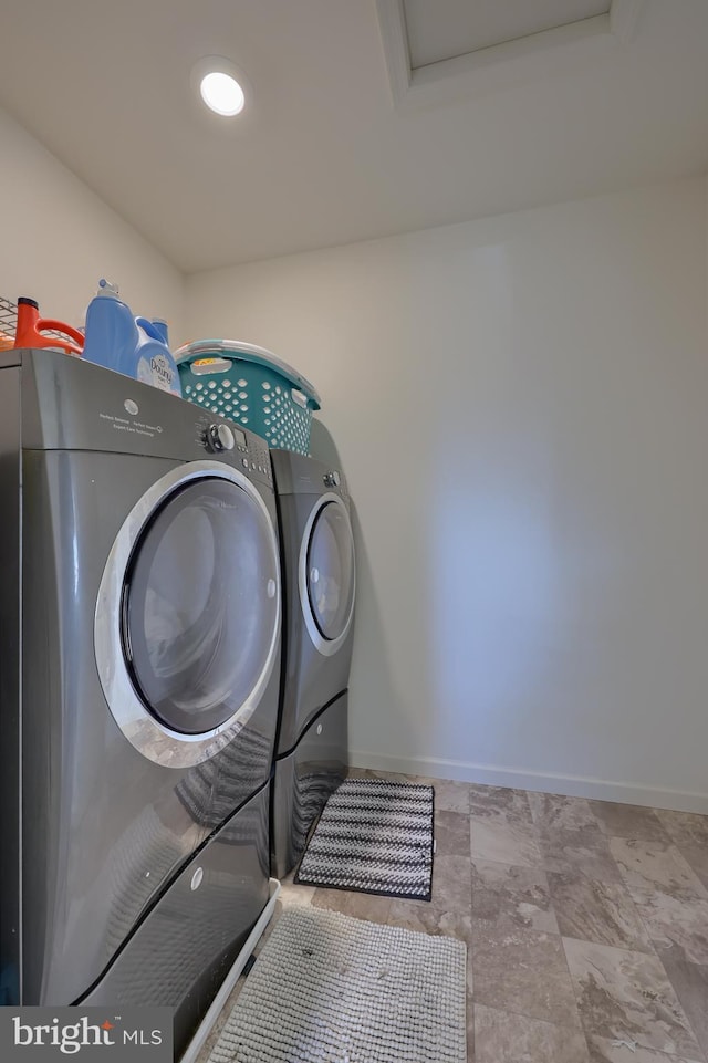 washroom with laundry area, washer and clothes dryer, and baseboards