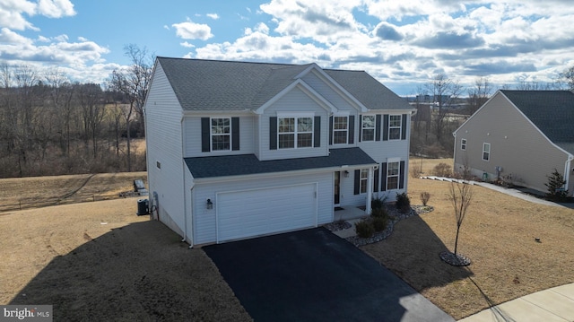 traditional home with a shingled roof, driveway, an attached garage, and central air condition unit