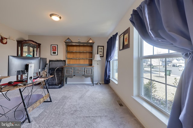 office space with carpet floors, plenty of natural light, visible vents, and baseboards