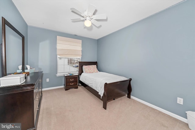 bedroom featuring light carpet, a ceiling fan, and baseboards