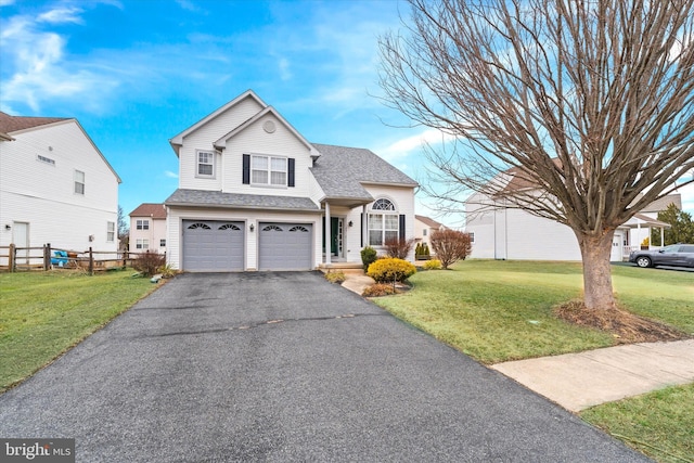 traditional-style house featuring a garage, driveway, a shingled roof, fence, and a front lawn