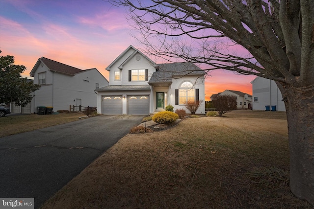 traditional home featuring a front yard, driveway, and an attached garage