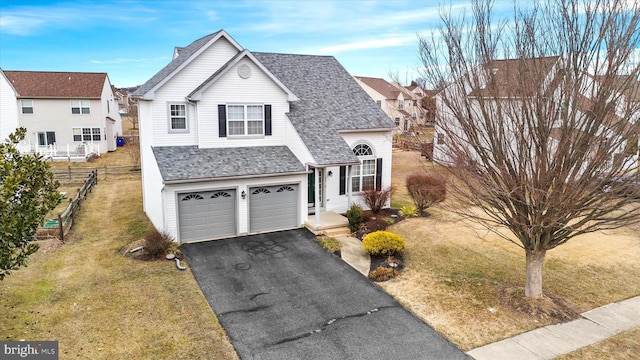 traditional-style home with a garage, a shingled roof, aphalt driveway, fence, and a front lawn