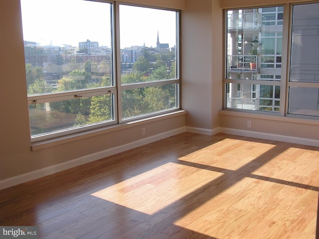 empty room with a city view, baseboards, and wood finished floors