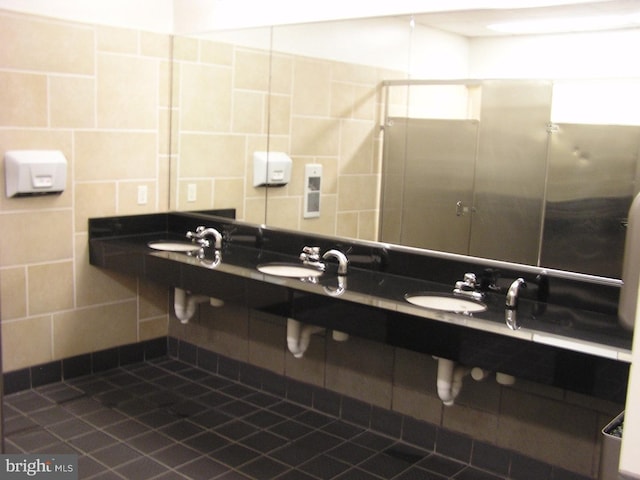 bathroom with tile walls, double sink, and tasteful backsplash