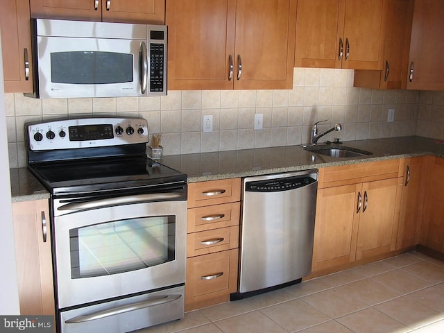 kitchen featuring light tile patterned flooring, decorative backsplash, stainless steel appliances, and a sink