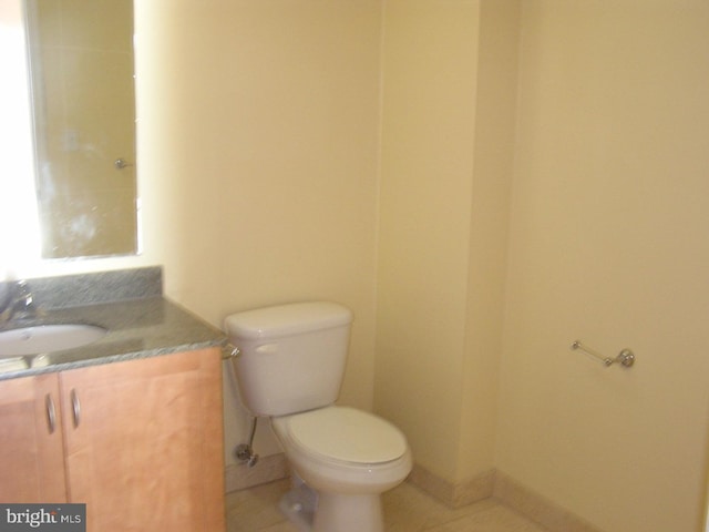 half bath with tile patterned floors, baseboards, toilet, and vanity