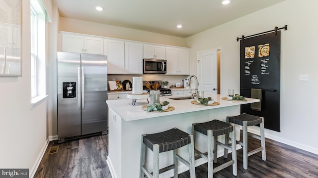 kitchen with dark wood finished floors, white cabinets, appliances with stainless steel finishes, light countertops, and a sink