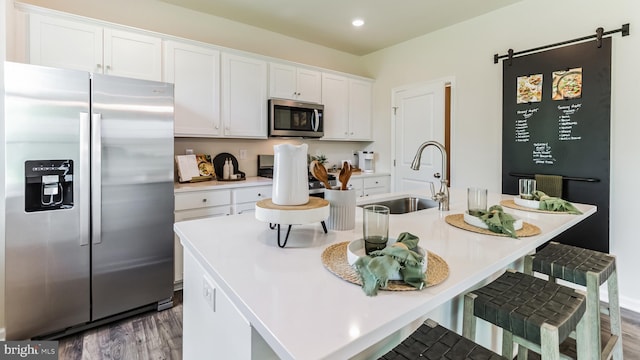 kitchen with white cabinets, a kitchen island with sink, stainless steel appliances, light countertops, and a sink