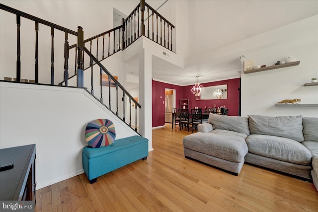 living area with a high ceiling, stairs, baseboards, and wood finished floors