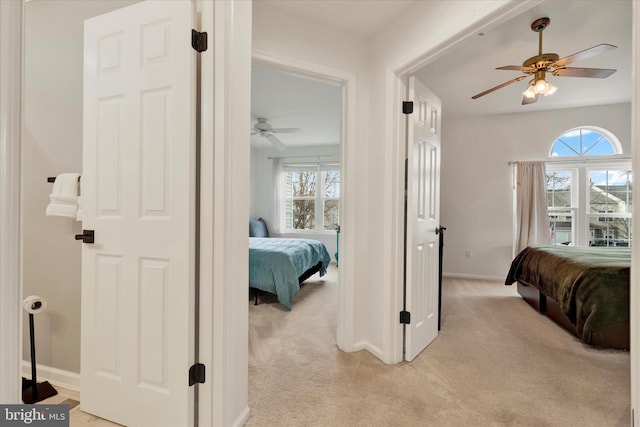 bedroom with light carpet, baseboards, and a ceiling fan