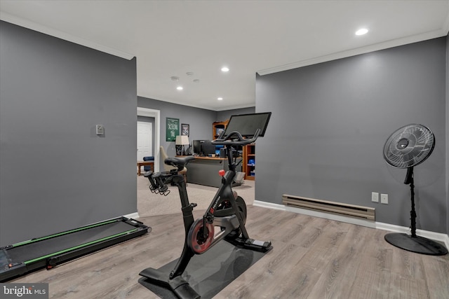 workout room featuring baseboards, baseboard heating, wood finished floors, and crown molding