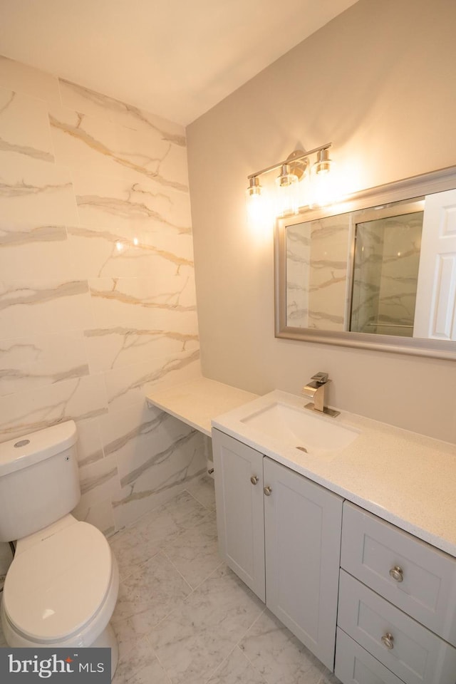 bathroom with marble finish floor, vanity, a shower stall, and toilet