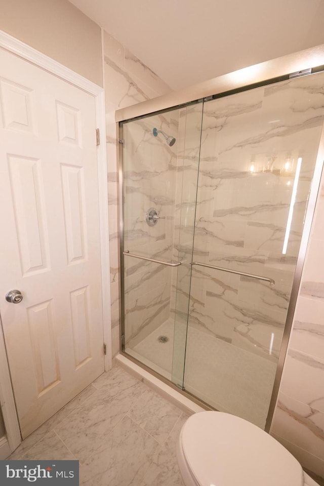 full bathroom featuring marble finish floor, toilet, and a marble finish shower