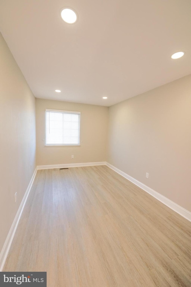 empty room with light wood-style floors, recessed lighting, visible vents, and baseboards