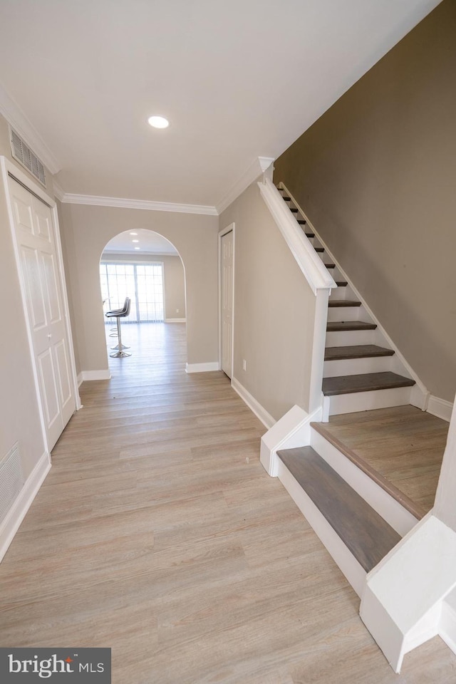 hall with arched walkways, crown molding, visible vents, wood finished floors, and stairs