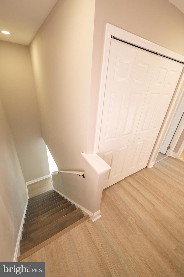 staircase featuring baseboards and wood finished floors