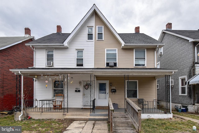 view of front of property featuring covered porch, a shingled roof, a chimney, and cooling unit