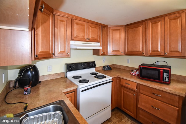 kitchen with under cabinet range hood, electric range, brown cabinetry, and a sink