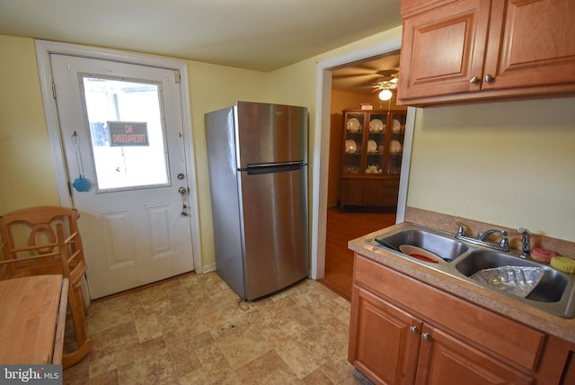 kitchen with brown cabinets, a sink, and freestanding refrigerator